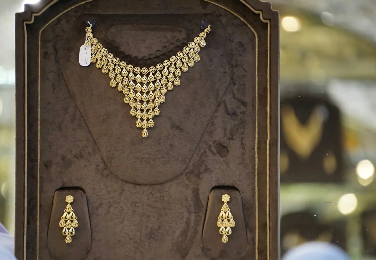 A gold necklace and earring set in a display case